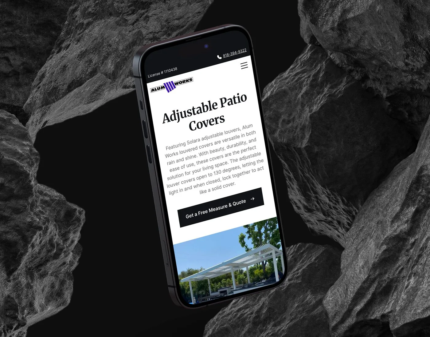 The Alum Works Adjustable Patio Covers product page on an iPhone angled among dark volcanic rocks — the product introduction above a photo of a white louvred pergola.