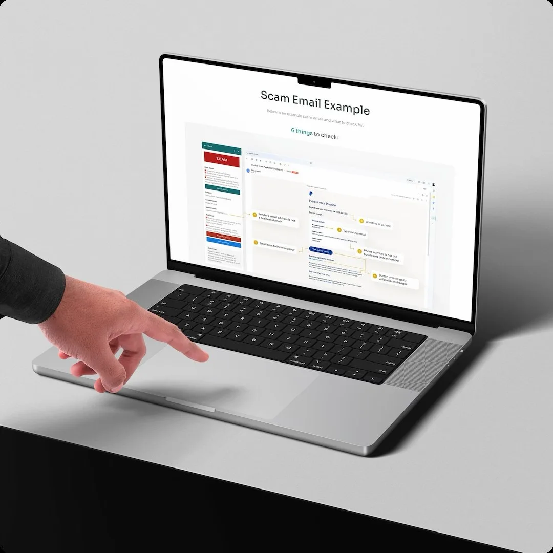 The Catch Scam Email Example page on a MacBook with a hand reaching to the trackpad, showing the 6 things to check diagram and its callouts for a generic greeting, a typo, urgency tactics and a sender address that is not a business domain.