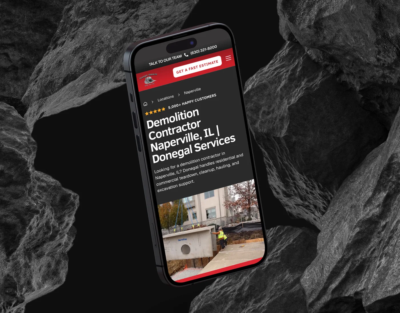 The Donegal Services Naperville service-area page on an iPhone angled among dark volcanic rocks, headed "Demolition Contractor Naperville, IL".