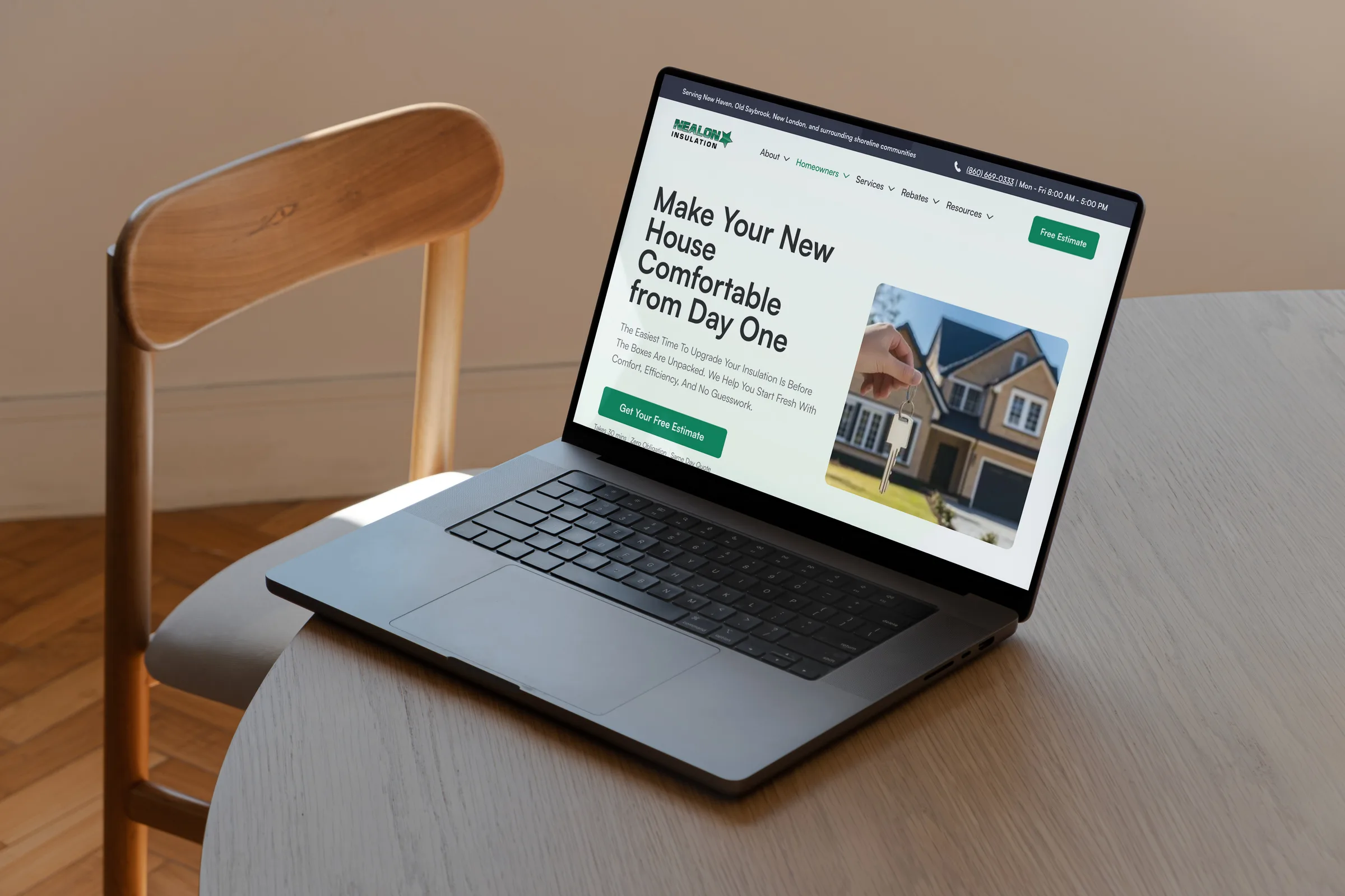 The Nealon Insulation purchased-a-home page on a MacBook at a light timber table — "Make Your New House Comfortable from Day One" beside a photo of house keys being handed over outside a new home.