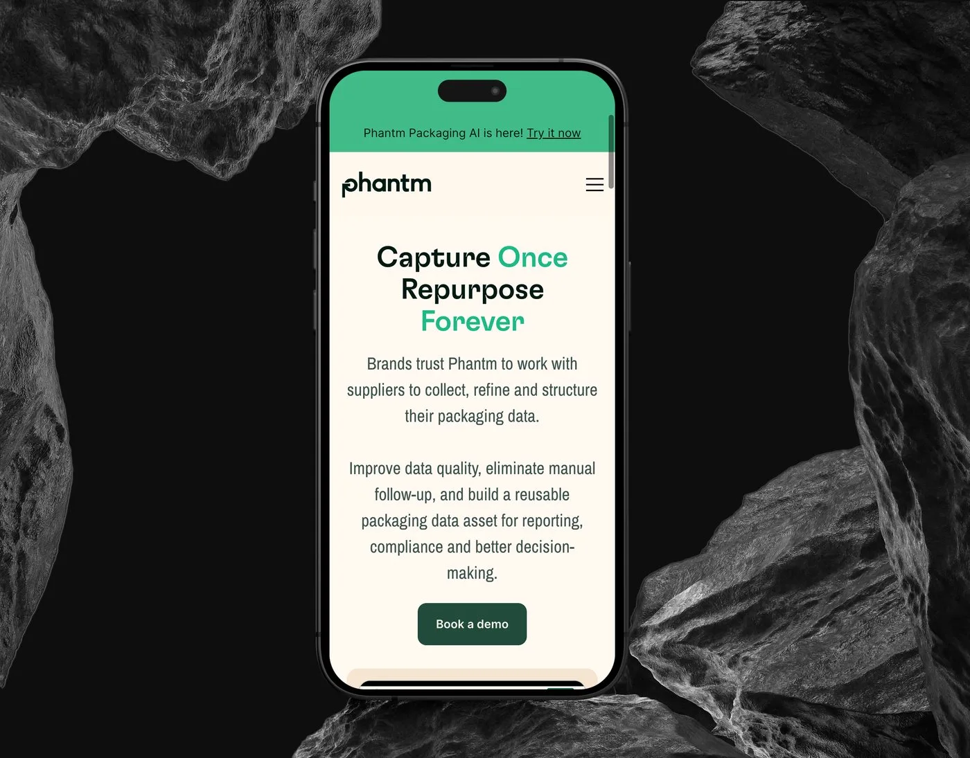 The Phantm mobile homepage on an iPhone set upright between dark rocks — the Capture Once, Repurpose Forever headline above the Book a demo button.