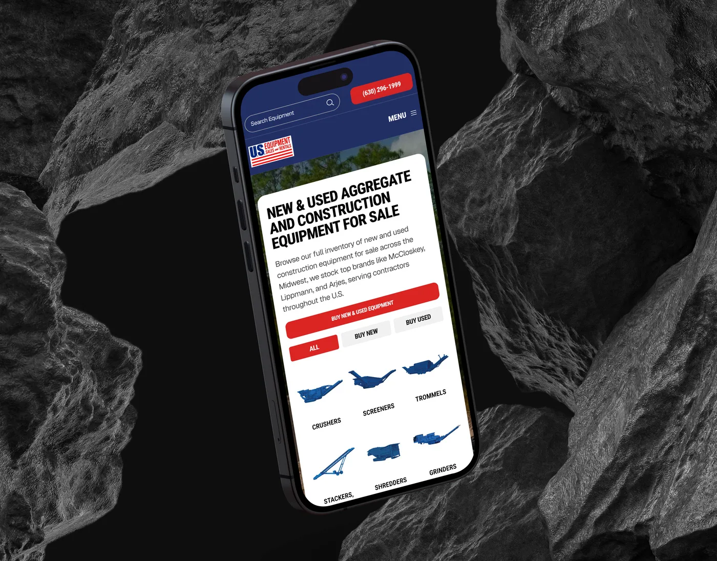 The US Equipment Sales inventory page on an iPhone angled among dark volcanic rocks, headed "New & Used Aggregate and Construction Equipment for Sale" above the equipment categories.