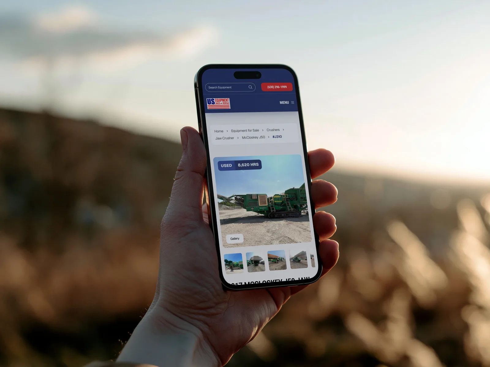 A US Equipment Sales machine listing on an iPhone held up outdoors at sunset: a used 2017 McCloskey J50 jaw crusher with its photos and hours.